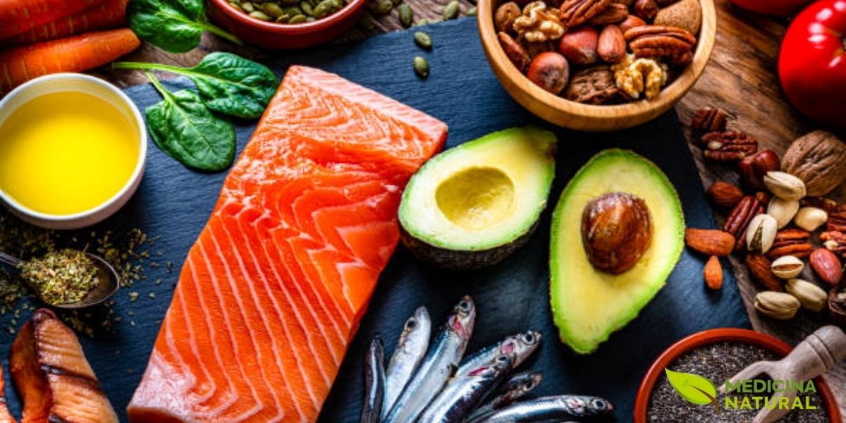 Variedade de alimentos contendo gorduras saturadas e insaturadas dispostos sobre mesa de madeira: salmão fresco, abacate, castanhas, nozes e azeite de oliva. As gorduras insaturadas (ômega 3, 6 e 9) presentes nestes alimentos ajudam a reduzir colesterol LDL, proteger o coração e melhorar função cerebral. Consumir esta diversidade garante perfil lipídico completo para saúde ótima.