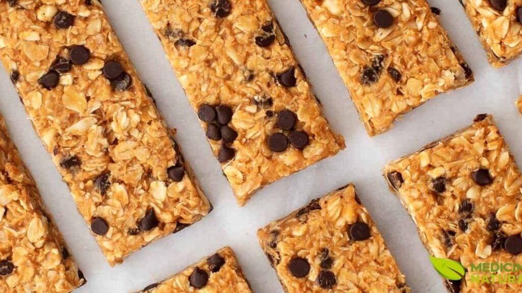 Barras de granola caseiras cortadas em porções uniformes e perfeitamente alinhadas sobre papel manteiga branco, demonstrando a técnica adequada de preparação e apresentação. A imagem exemplifica o resultado final de uma receita bem executada de barras de proteína pelo método a frio, onde a textura firme mas não dura permite cortes limpos e precisos.