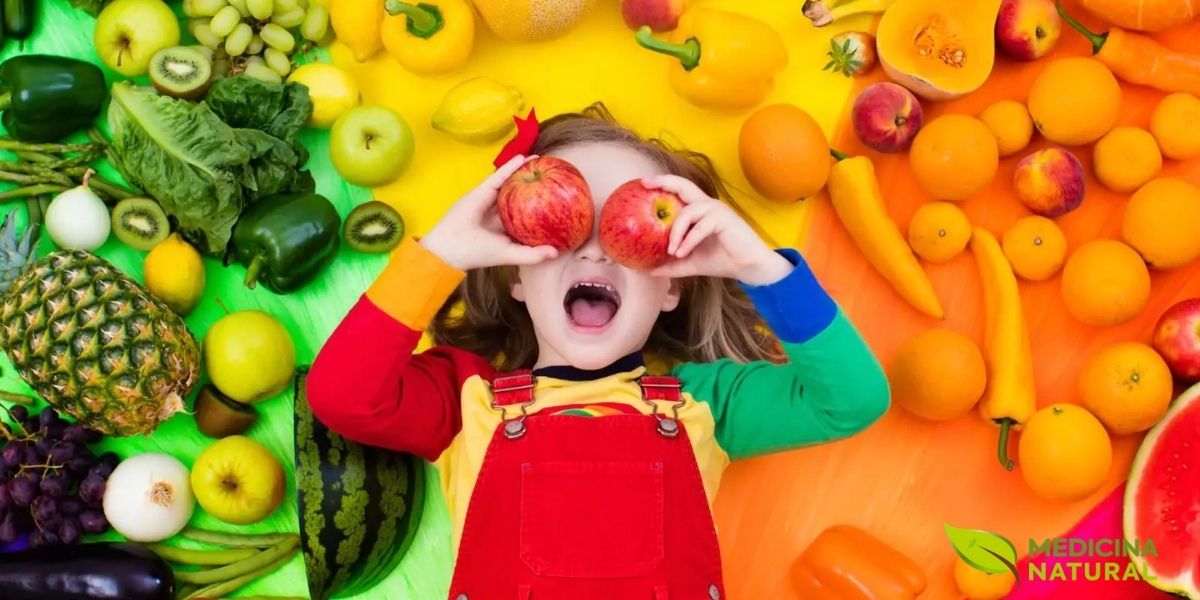 Uma criança radiante posando com uma abundância de frutas e vegetais frescos demonstra o entusiasmo que pode ser cultivado em torno de alimentos saudáveis. Envolver as crianças na escolha, compra e preparação de alimentos coloridos pode transformar a resistência em curiosidade e aceitação.
