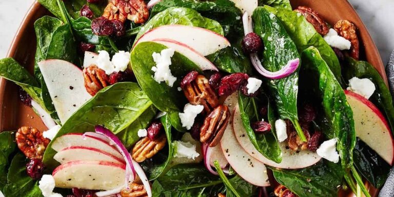Salada com folhas de espinafre, fatias de maçã, nozes-pecã e cranberry